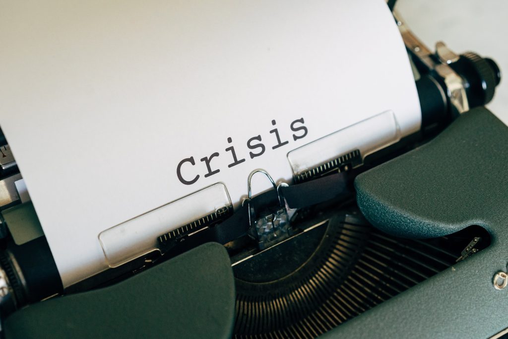 Close-up of a vintage typewriter with a sheet of paper that reads the word 'crisis'.